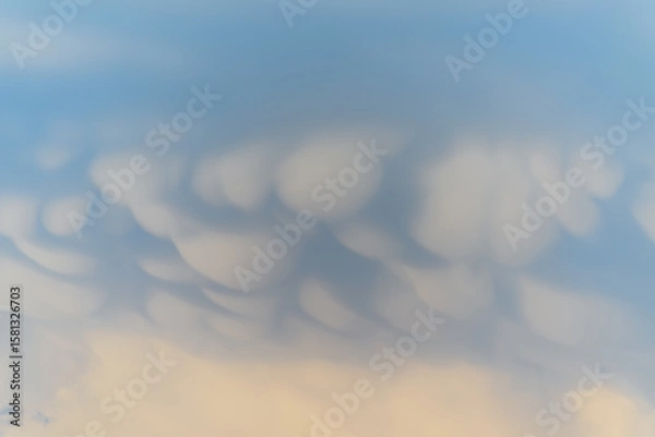 Fototapeta Unique cloud formations display dramatic textures during sunset over the landscape