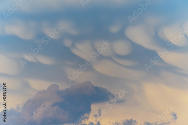 Fototapeta Unique cloud formations display dramatic textures during sunset over the landscape