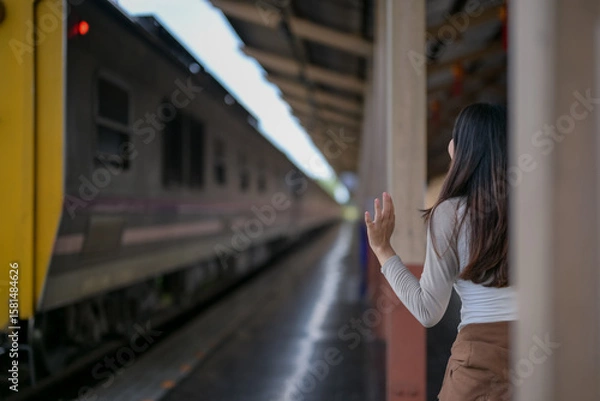 Fototapeta A woman stands on the platform of a train station