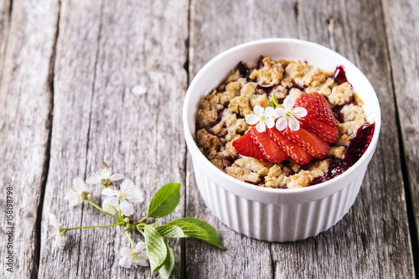 Fototapeta Strawberry blackberry crumble with oatmeal crispy crust on vintage rustic wooden table. Healthy breakfast. Summer baking. Diet. Selective focus 