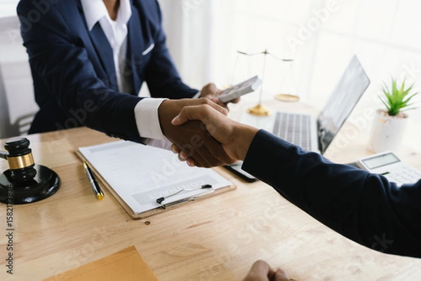 Fototapeta Close-up of lawyer giving legal advice showing professional handshake which is a symbol of fairness, agreement, trust and successful negotiation between lawyer and client in business or court.