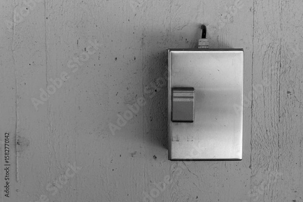 Fototapeta Metal switch plate on a textured wall illuminated by soft light brings a modern touch to minimalistic design aesthetics in a cozy space