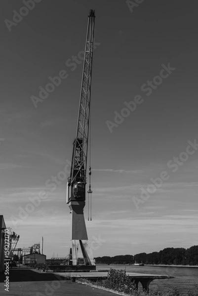 Fototapeta Industrial crane towers over the serene waterfront, capturing the essence of maritime life in a quiet harbor at dawn