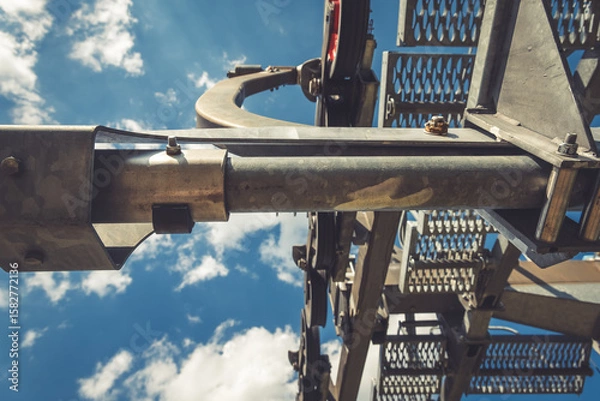 Fototapeta Elevating machinery against a backdrop of vibrant blue skies and fluffy clouds showcasing industrial engineering at its finest in mid-day light
