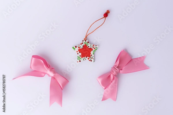 Obraz Festive Christmas decoration featuring a red ribbon arranged on a white background. Flat lay, top view style. Ideal for holiday cards, invitations, and seasonal designs.