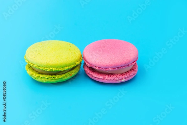 Obraz Mixed of colorful macaroni or pasta cake on a blue background. Sweet and colorful french macarons. Two multi-colored green and pink macaroons. Culinary and cooking concept, styling food.