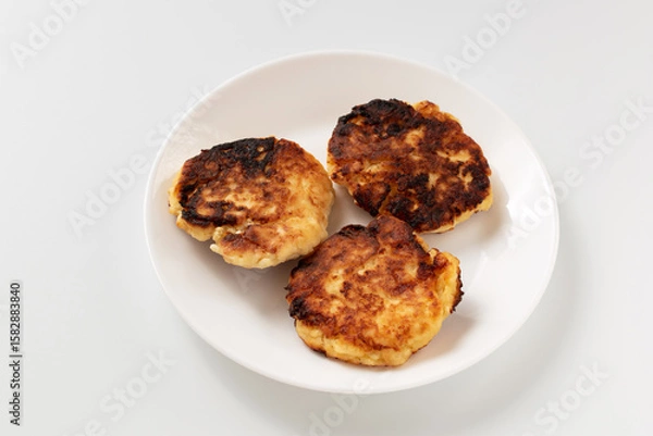 Fototapeta Tasty cottage cheese fritters. Curd pancakes in a white plate on a table. Top view.