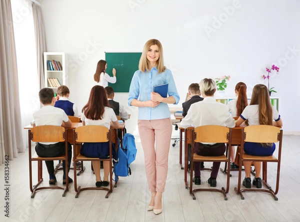 Fototapeta Female teacher with notebook in classroom