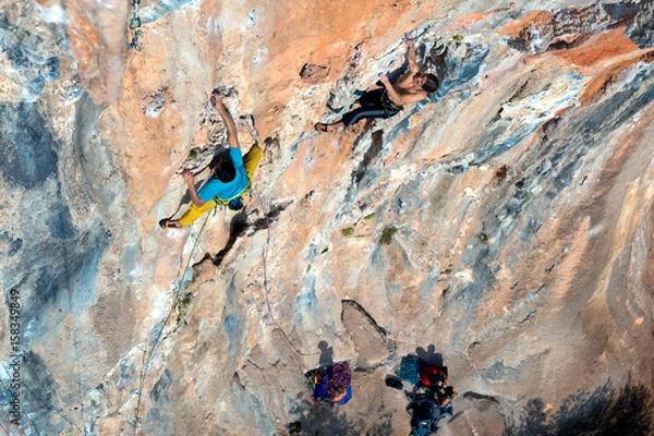 Obraz Two Rock Climbers moving up on vertical Wall high