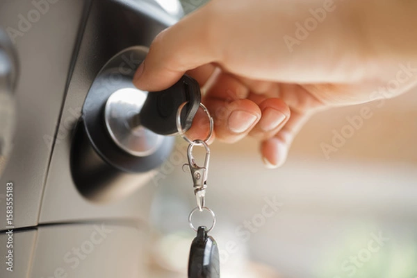 Fototapeta Hand inserting a car key into the ignition switch in a vehicle dashboard 
