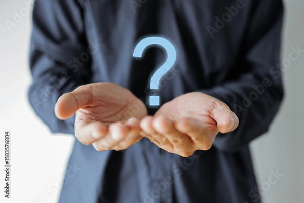 Fototapeta Businessman holding a question mark symbol representing confusion and uncertainty