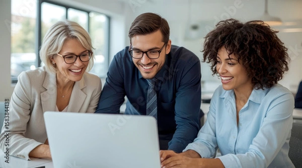 Fototapeta Laptop, collaboration and business people in the office while working on a company project. Technology, joyful group of three diverse professionals gathered around a laptop in a bright, modern office