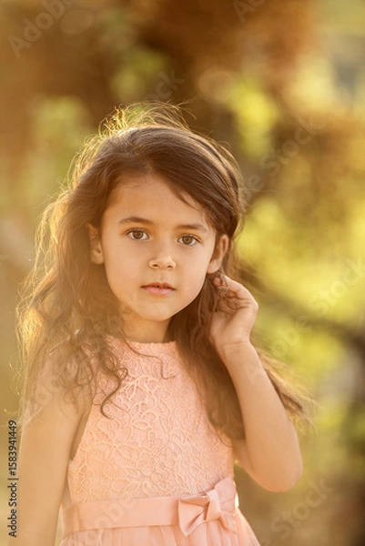Fototapeta Portrait of a child girl  standing in nature  and looking at camera at sunset time