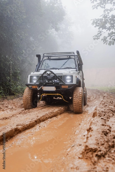 Fototapeta Off-road vehicle running on a muddy road.Close-up of an off-road vehicle tire kicking up dust and dirt on a rugged terrain.