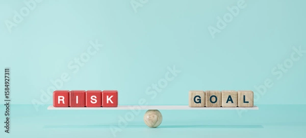Fototapeta Wooden blocks spelling “RISK” and “GOAL” balanced on seesaw plank with sphere base. Concept of risk management, business strategy, investment decision, life goals.