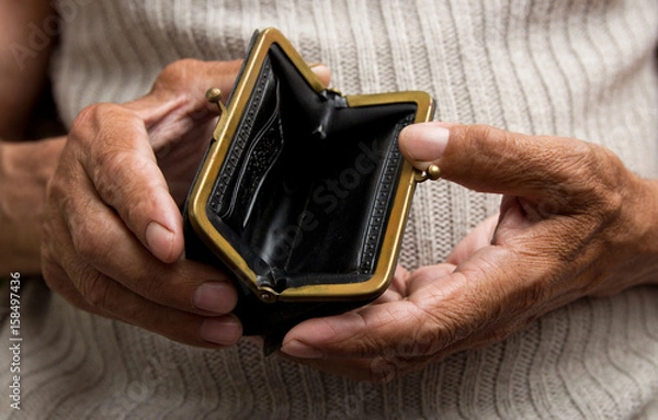 Fototapeta An elderly man holds an empty purse. The concept of poverty in retirement .