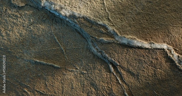 Fototapeta Close-up of cracked sandstone with layered white mineral vein and warm light