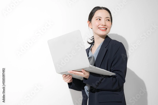 Fototapeta パソコン持って立つ振り返るの若いかわいい女性のビジネスイメージ上半身