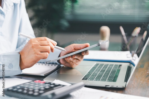 Fototapeta Office businesswoman hand to operate calculator analyzing financial data, counting costs on desk. accounting, financial analysis for business budget planning, calculation support, finance management.