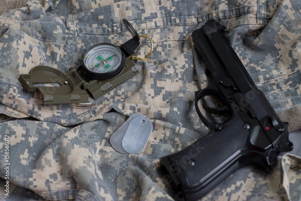 Obraz Army badge, pistol and compass on the background of camouflage
