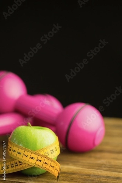 Fototapeta Pink dumbbells with green apple and measuring tape