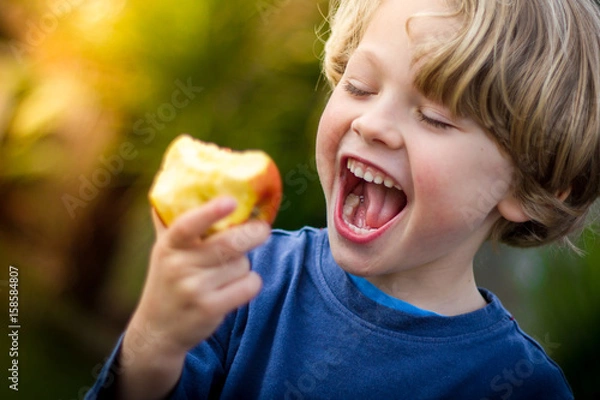 Obraz słodkie blond dziecko, które chce ugryźć jabłko