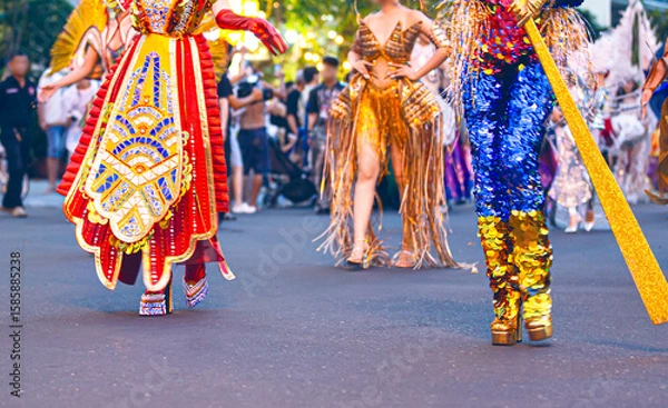 Fototapeta Close-up of women's legs in colorful carnival costumes at the Nha Trang Marine Festival carnival. Shiny fabrics, feathers, heels, movement, festive atmosphere. selective focus