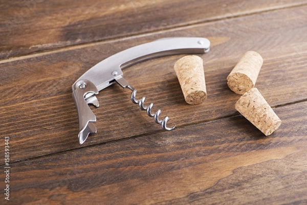 Fototapeta Close-up of corkscrew next to several corks. Horizontal studio shot.