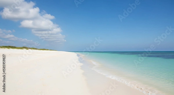 Fototapeta A pristine, white sand beach stretching into the distance, with calm, turquoise water gently lapping the shore. The sky is a clear, bright blue, and a few fluffy white clouds are scattered above. The 