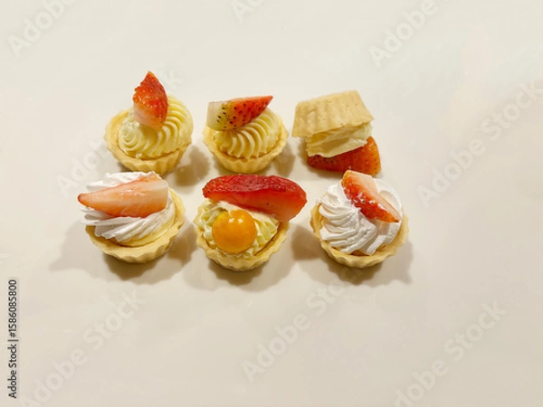 Fototapeta Delicious mini fruit tarts arranged next to each other, with one flipped over.