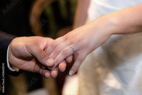 Fototapeta Close-up hands of bride and groom putting on a wedding rings