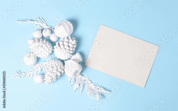 Fototapeta White colored Pine cones, branches, physalis flowers and with empty gift card. Flat lay minimal concept.