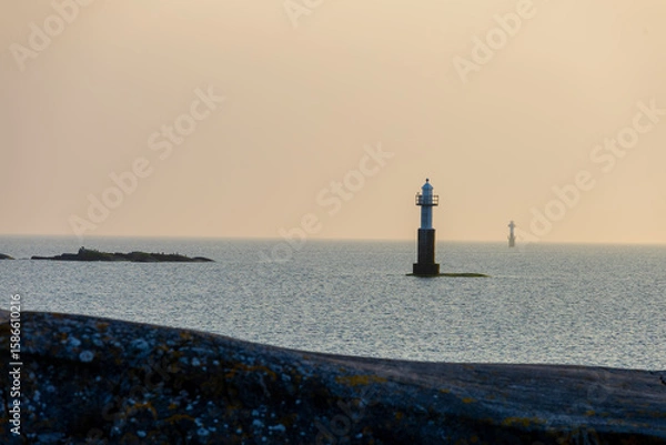 Obraz Two solitary lighthouses stand in calm waters under soft evening light. A serene seascape with Nordic minimalism and peaceful tones.