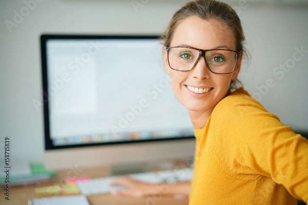 Fototapeta Cheerful trendy girl working on desktop computer