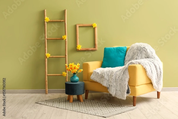 Fototapeta Cozy armchair with plaid, ladder and daffodil flowers in living room