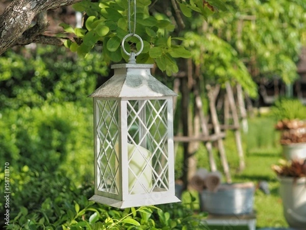 Obraz White Iron lantern hanging on tree in the garden. Concept of exterior decoration.