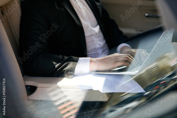 Obraz Businessman typing in a car