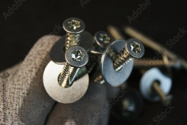 Obraz Construction worker holding large bolts with washers. Construction work process.