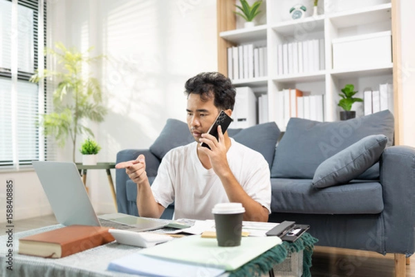 Fototapeta A man is spending his time on his holiday activities. He reads books, plays with his phone, laptop, deals with bills, and plays games during his leisure time.
