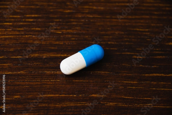 Fototapeta Pill, vitamin on wooden table, dark background with space for text. Self-medication concept.