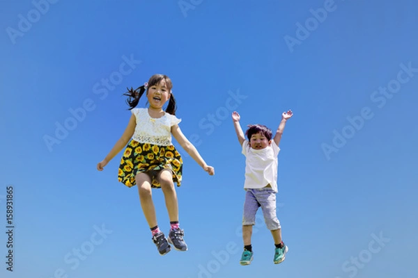 Fototapeta 青空バックにジャンプする子供2人