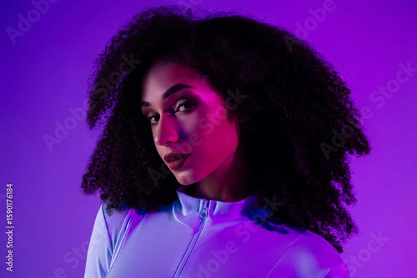 Obraz Trendy woman in a stylish jumpsuit illuminated by neon lights against a violet background, expressing beauty