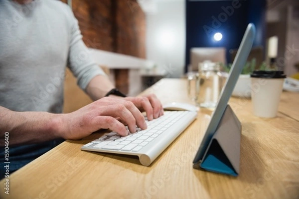 Fototapeta Male executive using digital tablet at desk in office