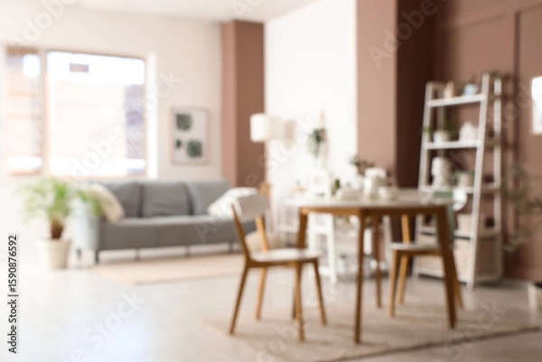 Fototapeta Blurred view of living room with green plants, sofa and dining table