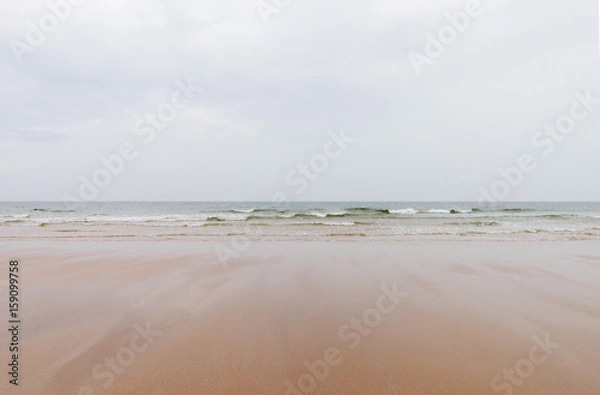 Fototapeta sandy beach and wavy sea surface on the wales coast on a cloudy day