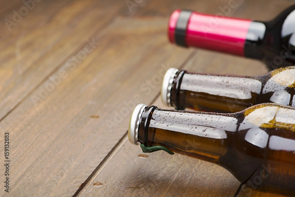 Fototapeta Close-up of two beer bottles and one wine on wooden table. Copy space.