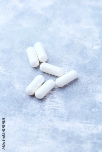 Fototapeta Creatine capsules on bright wooden background. Soft focus. Close up. Copy space.