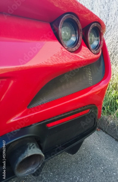 Fototapeta View of a section of the rear of a modern, high-end, red Italian sports car with a stunning design representing beauty, wealth and luxury