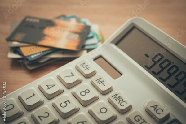 Fototapeta White calculator shows minus delinquent and many credit cards on wooden table background. Credit card debt loan, personal financial problem, bank high interest rate, bankruptcy and so on concept.
