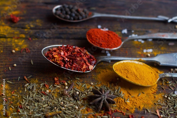 Obraz colorful spices in vintage silver spoons on rustic wooden background, selective focus 